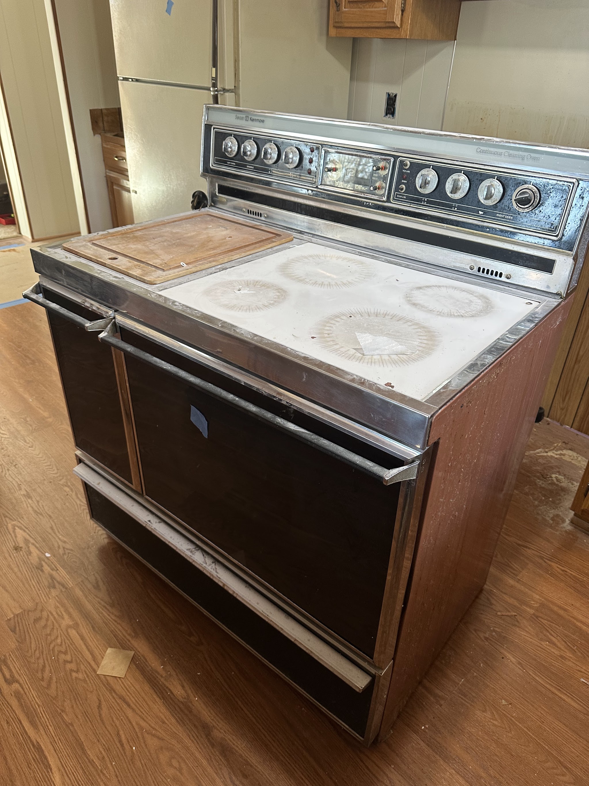 An old double oven range sitting in a kitchen, ready to be hauled
