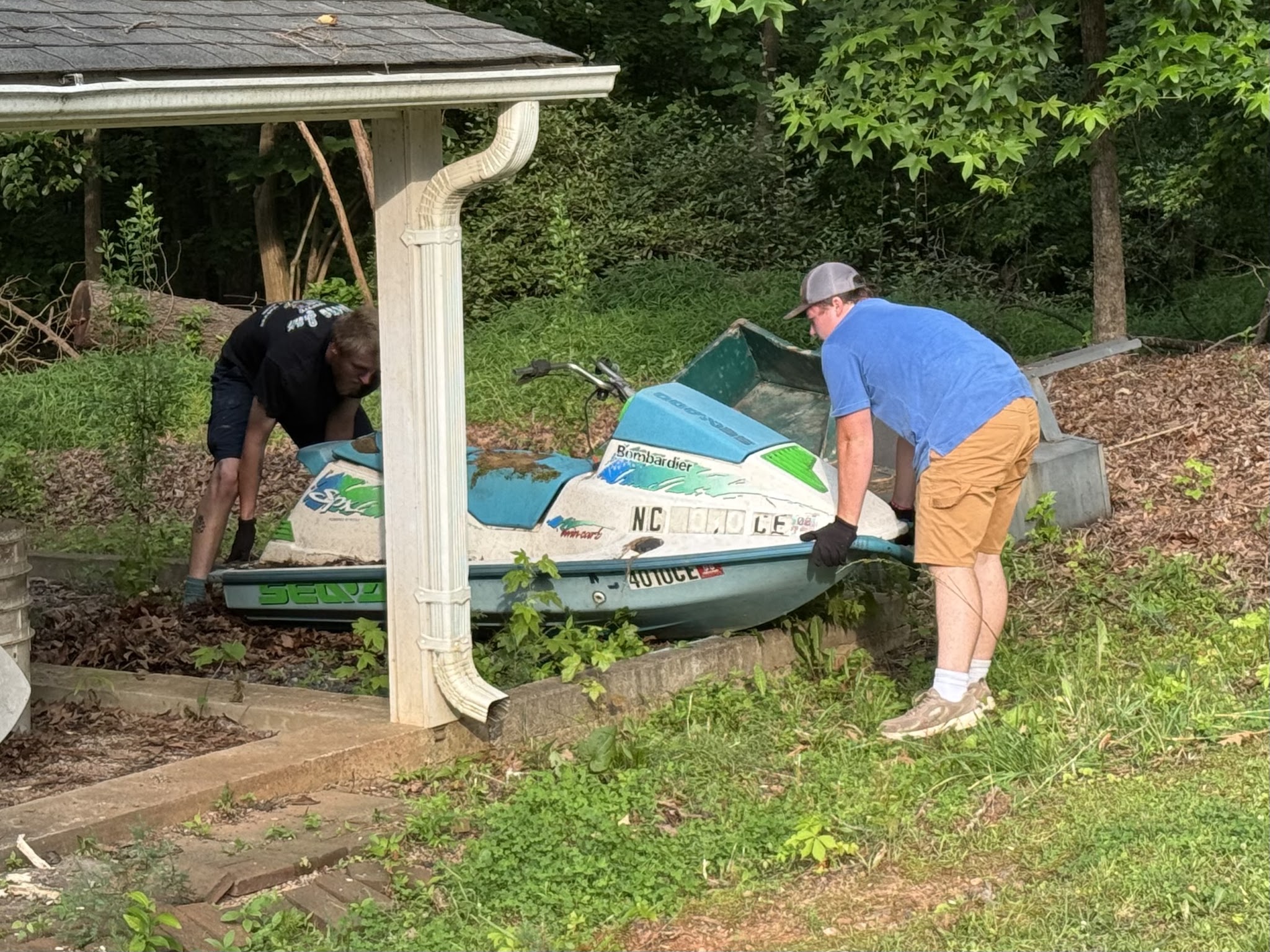 Two of us lifting an old jet ski out of a yard
