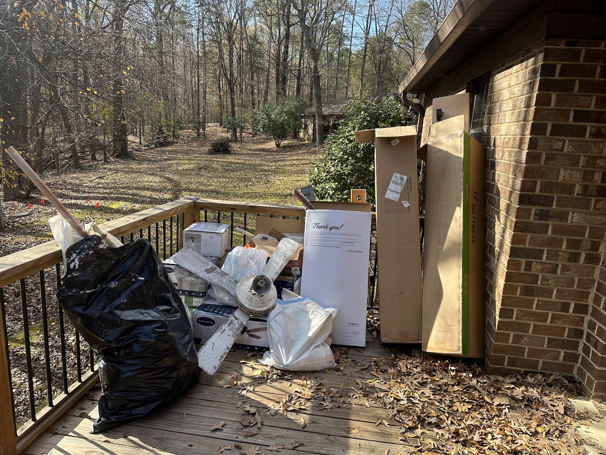 A pile of boxes, a ceiling fan and bags on a deck, ready to go